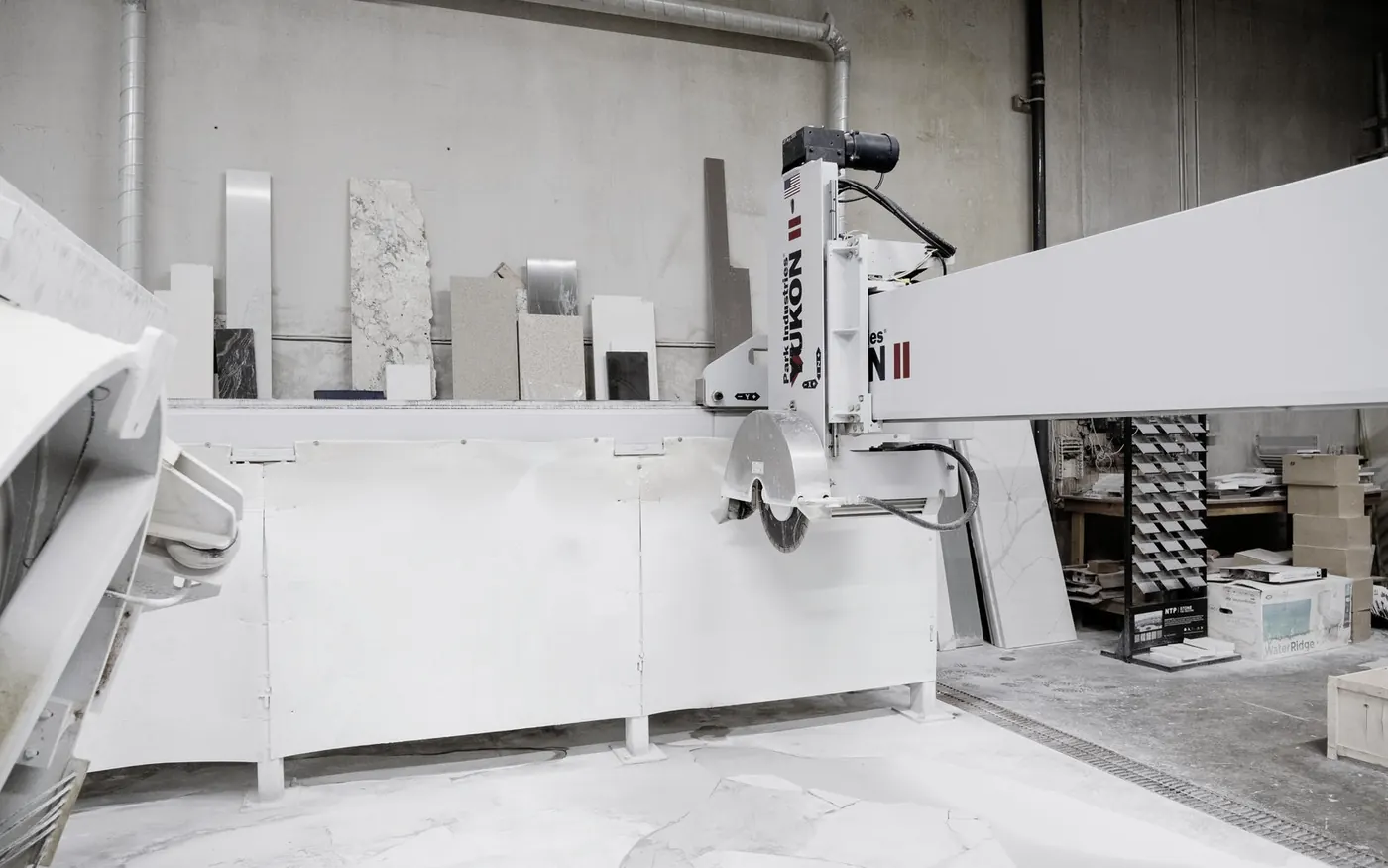 Stone cutting machine in a workshop with stone samples on the shelves behind